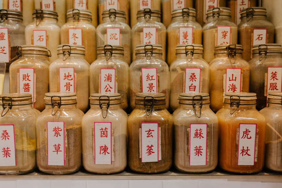 Rows of herbal medicine jars with Chinese labels in an apothecary