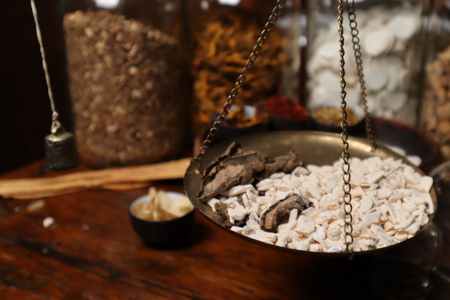 Dried herbs being weighed on a traditional balance scale